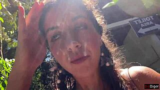 in the public locker room, she gets cum on her face, then walks to the waterfall with it