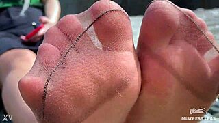 Jumalatar ruskeissa nylooneissa näyttää kivat nylon-jalkapohjat ja varpaat jokivarressa