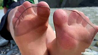 goddess in tan nylons shows her cute nylon soles and toes on the riverside