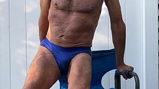 Exhibitionist Stretches Deeply In Blue Briefs On Chair