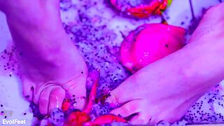 Bare toes crushing juicy fruit in a fun way