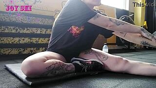 this alternative girl with tattoos stretches at the gym