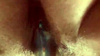 She masturbates her hairy pussy with a glass dildo up close