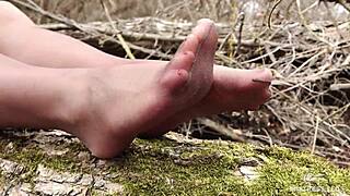 goddess teases feet in tan pantyhose through spring forest leaves
