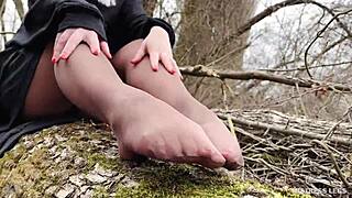 goddess teases feet in tan pantyhose through spring forest leaves